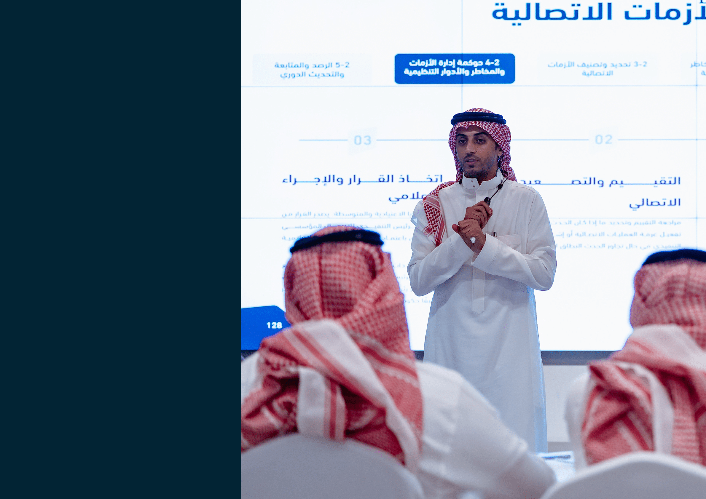 شخصان يرتديان ملابس تقليدية عربية يقفان أمام شاشة عرض كبيرة تحمل شعار وأسم أكاديمية ون مكتوب بالعربية والإنجليزية في مكان داخلي حديث. Description generated by AI