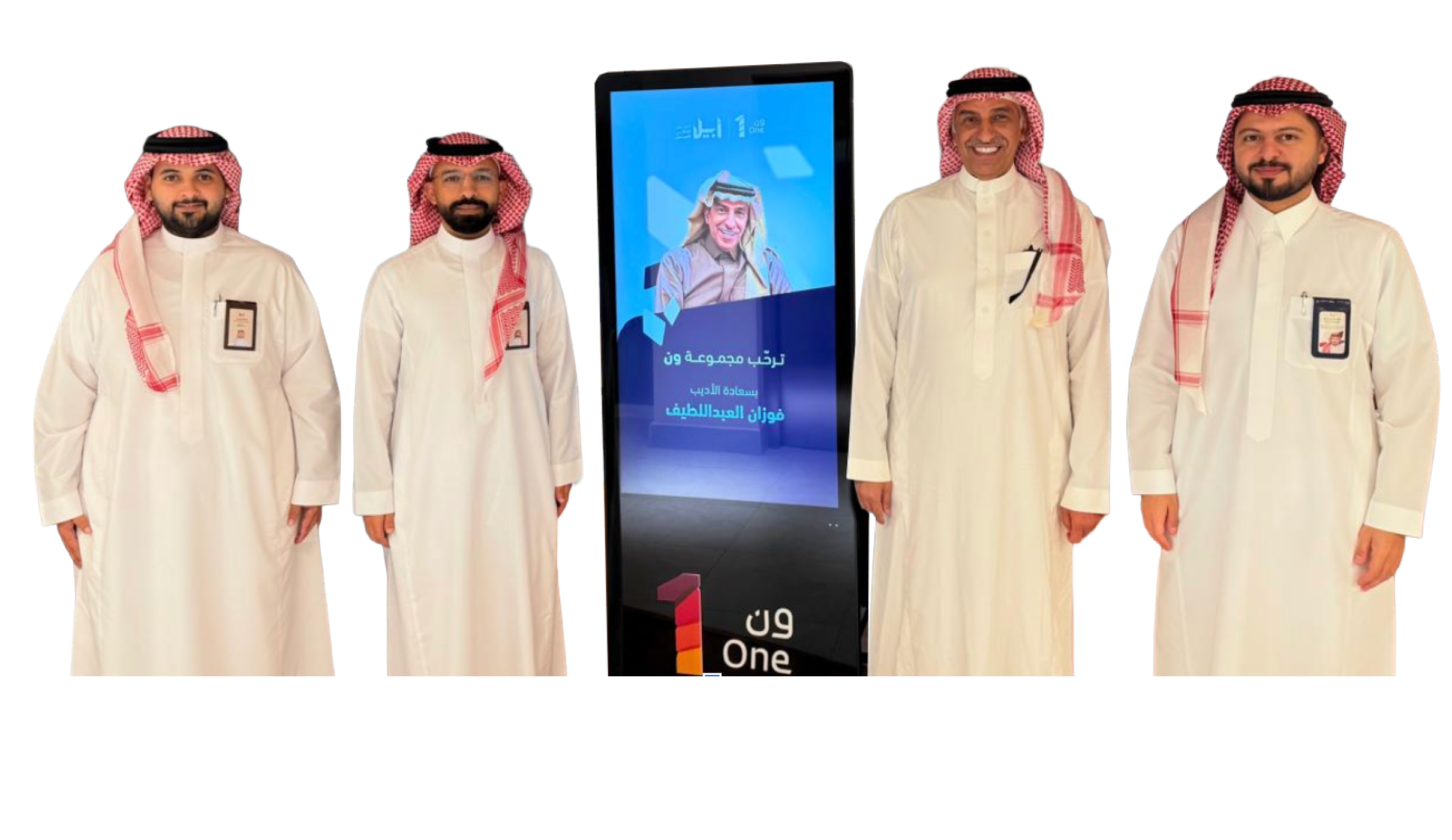 أربعة أشخاص يرتدون الثوب والشماغ يقفون بجانب شاشة رقمية تعرض صورة ونص باللغة العربية. Description generated by AI